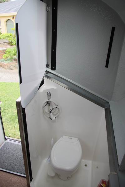 Het vacuum toilet en binnendouche. 
Een privacyscherm is omgeklapt boven de tussenwand. 
Om te douchen is er een douchewand die met klittenband vastgezet wordt.  
Er is ook een buitendouche in het achterluik en we hebben een douchetent gekocht.  
Het vacuum toilet heeft geen chemicalien nodig, zodat de cassette overal geleegd kan worden, ook in bushtoilets of desnoods in een gat in de grond.